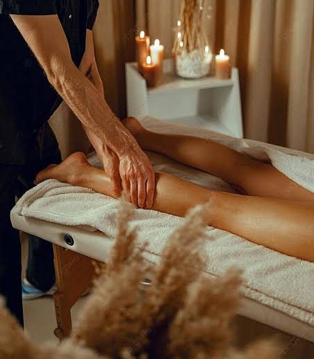 Terapeuta massageando as pernas de uma cliente à luz de velas