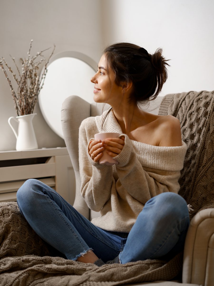 Mulher sentada numa poltrona, em pausa, segurando uma caneca de chá